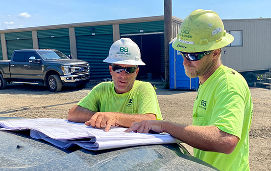 Brubacher employees in the field looking at plans