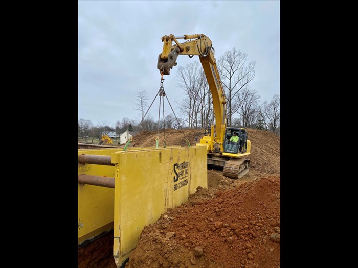 excavator swinging trench box into place