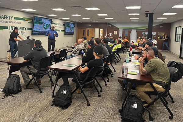 Photo of Jordan K. and Melvin P. in the training room, addressing new team members from the Abel Construction acquisition