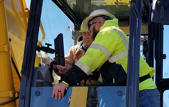 Brubacher Employees in field in excavator cab looking at screen