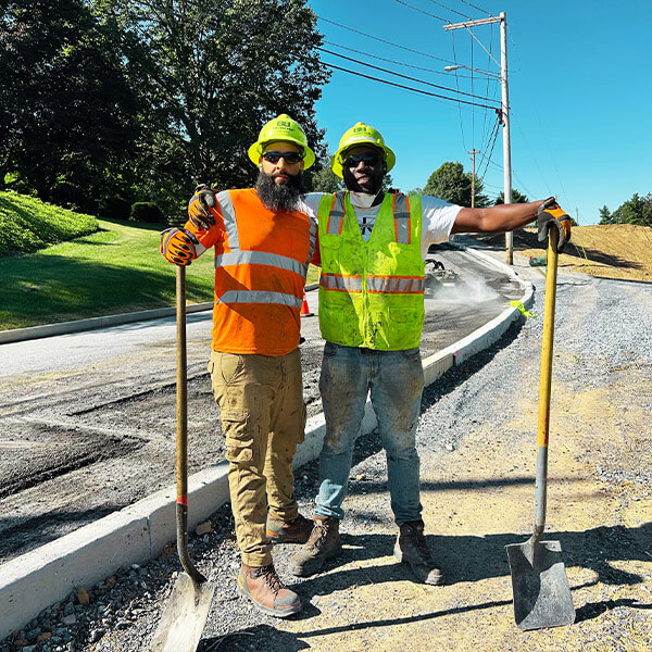 Two Brubacher employees smiling with arms around each other on job site.