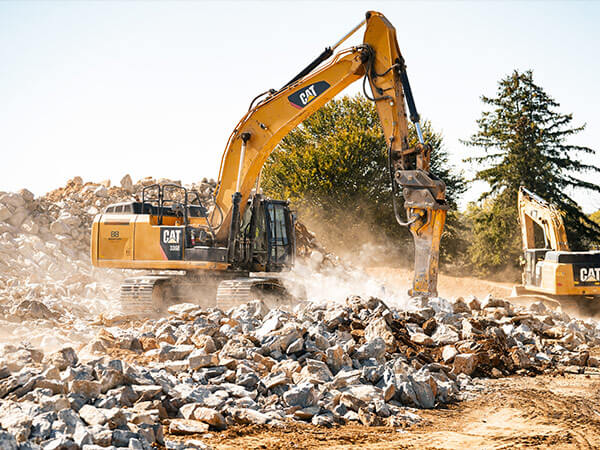Large piece of construction machinery on job site while breaking up rocks.